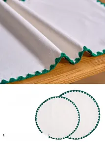 Close-up of white cotton placemats with green wavy embroidery and shell ripple edges