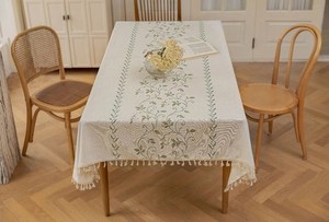 Detail of green vine embroidery and cream tassels on a rectangle linen tablecloth