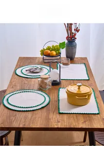 Detail of embroidered Nordic placemats with green wavy edges on a wooden dining table