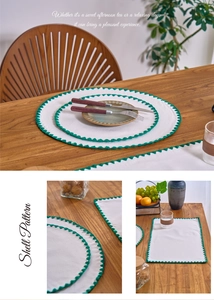 Detail of cream cotton linen placemat with green scalloped crochet shell edge embroidery