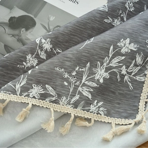 Grey rectangular linen tablecloth with white floral prints and decorative beige tassels