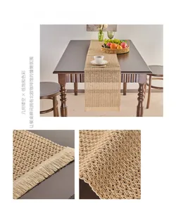Detailed macro view of khaki woven table runner with tassels and hollow mesh patterns