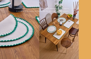 Detail of cream placemat with green scalloped embroidery edges on a wooden table