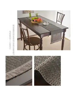 Close-up of gray hollowed-out woven table runner with decorative paper fringe details