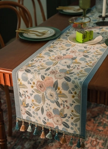 Detailed view of floral jacquard table runner with decorative colorful fringe tassels