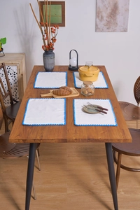 Detail view of 4-piece white placemat set with blue scalloped edges on a wood table