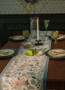 Detail of floral jacquard table runner with golden accents and blue fabric texture