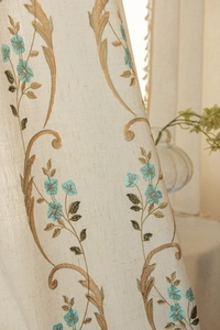 Vue détaillée des broderies florales et de la texture en lin sur un rideau élégant
