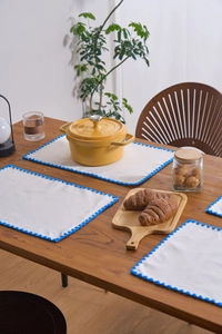 Set of 4 cream fabric placemats with blue scalloped edges for heat insulation on wood table