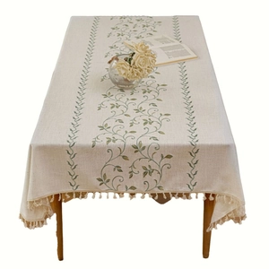 Rectangular beige cotton linen tablecloth featuring green vine embroidery and tassel edges
