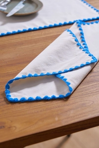 Detailed shot of white cotton linen placemat with blue crochet edge on wooden table
