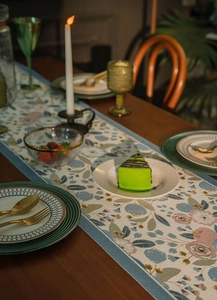 Detail of floral table runner with blue jacquard fabric and tassel fringe decoration