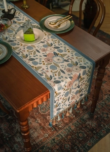 Close-up of floral jacquard table runner with decorative tassel trim and vintage pattern