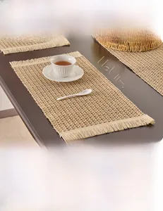 Detailed close-up of natural paper braided placemat with fringed edges on wood table