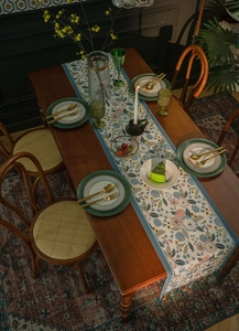 Close-up of pastoral floral table runner with colorful tassels on dark wood table