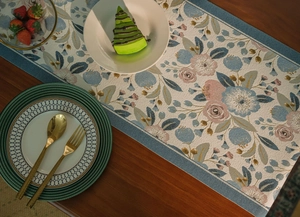 Detailed jacquard table runner with floral patterns and tassels on wooden surface