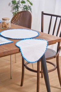 Detail of white felt placemat with blue scalloped edge stitching on wooden table