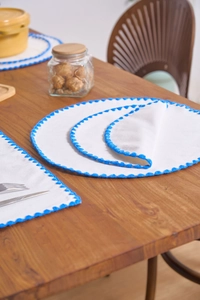 Detailed view of white cotton-linen placemats with blue embroidered scalloped borders