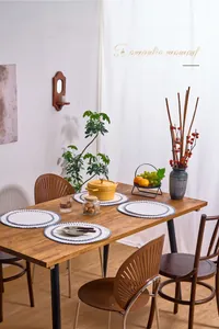 Detail of white round cotton linen placemats with blue wave embroidery on a wooden table