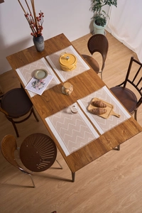 Detailed view of beige and brown geometric woven placemats with soft fringe on wooden table