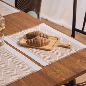 Macro view of woven placemat featuring geometric jacquard patterns and delicate fringe