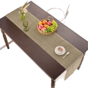 Rustic hollow woven table runner in light brown with decorative fringe on a wood table