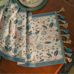 Floral jacquard table runner with fringe tassels on a wooden dining table background