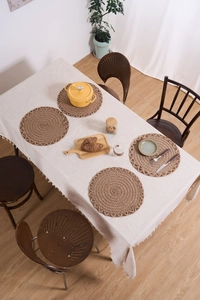 Close-up of four dark brown round woven placemats with hollow wavy edges on linen cloth