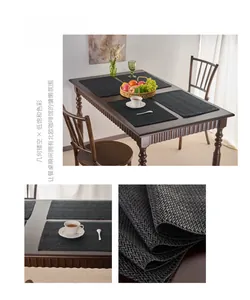 Detail of black woven placemats with geometric hollow pattern and fringed edges