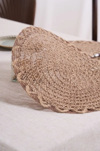 Close-up of circular braided jute placemat with natural spiral texture on beige tablecloth