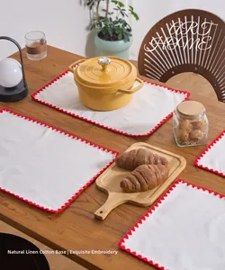 Close-up of beige linen placemat with intricate red floral embroidery on a wooden table