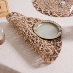 Detail of woven brown placemat with hollow grid texture and scalloped edges for dining