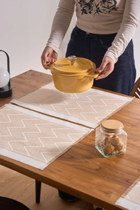 Detail of woven jacquard placemat with fringe on a wooden table for dining setup