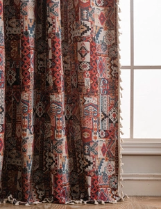Vista dettagliata delle tende jacquard con motivi geometrici e nappe bianche in stile boho