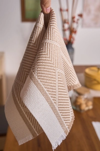 Close-up of beige jacquard placemat with herringbone patterns and delicate fringe