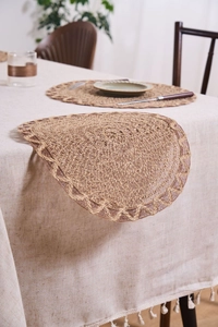 Close-up of woven round placemat with scalloped edges on a linen tablecloth