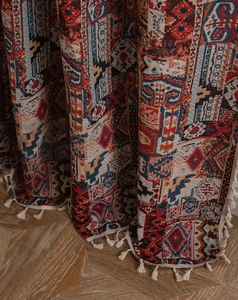 Dettaglio della tenda bohémien geometrica con motivi jacquard e nappine bianche fatte a mano