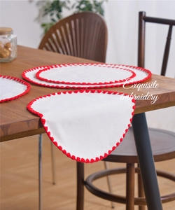 Close-up of exquisite red scalloped embroidery edges on white linen table placemats