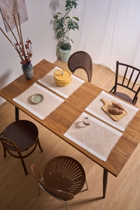 Close-up of geometric jacquard woven placemat with fringed edges on dark wood table