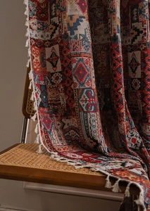 Dettaglio di coperta bohémien geometrica con frange bianche su una sedia di rattan
