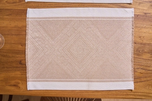 Macro detail of Nordic woven placemat with beige geometric patterns and fringed edges