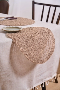 Detail of round braided jute placemat showing natural woven texture and rustic table decor
