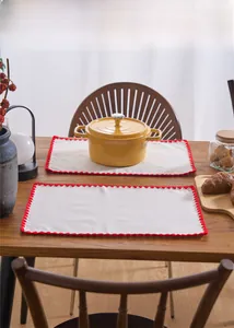 Detail of rectangular beige cotton linen placemat with red scalloped crochet embroidery