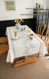 Detail of faux linen tablecloth showing green vine embroidery and fringe tassels