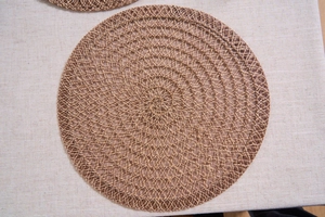 Detail of hand-woven round jute placemat with natural spiral texture and heat resistance
