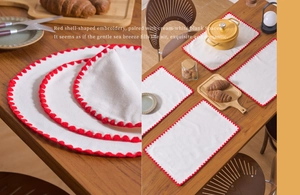 Detail of cream cotton placemat featuring red scalloped embroidery and wavy edges
