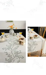 Close-up of white linen tablecloth with green leaf embroidery and white fringe details