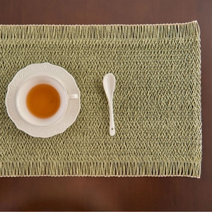Handwoven sage green sage rectangle placemat with tassels on dark wooden table
