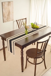 Detail of modern black and white striped table runner on a dark wood dining table