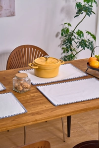 Close-up of American pastoral placemat with blue scalloped embroidery on wood table